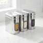 Set of three Ebun stainless steel kitchen storage containers with windowed fronts on a white surface.