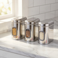 Set of three Ebun stainless steel kitchen canisters on a marble countertop with visible brand name.